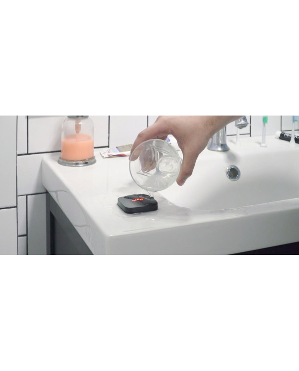 Balts noplūžu sensors ar LED indikatoru un uzstādīšanas pamatni, novietots uz balta fona.