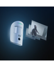 Balts kustību sensors ar kameru, uzstādīts uz sienas, ar LED indikāciju un modernu dizainu.